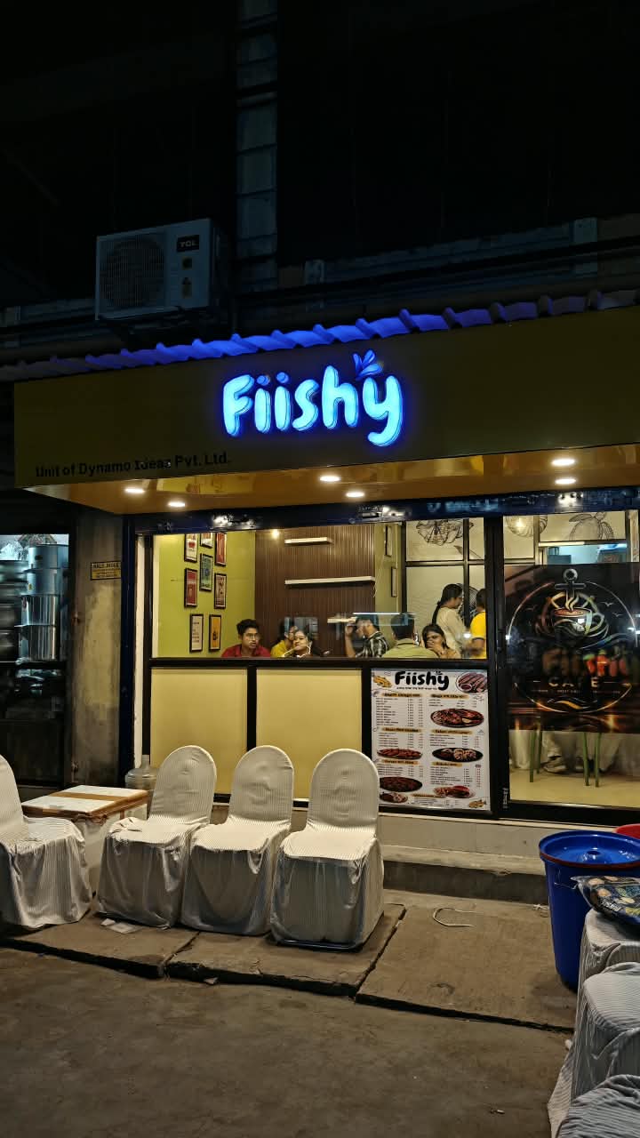 The shopfront by night, Fiishy written in blue over yellow.
